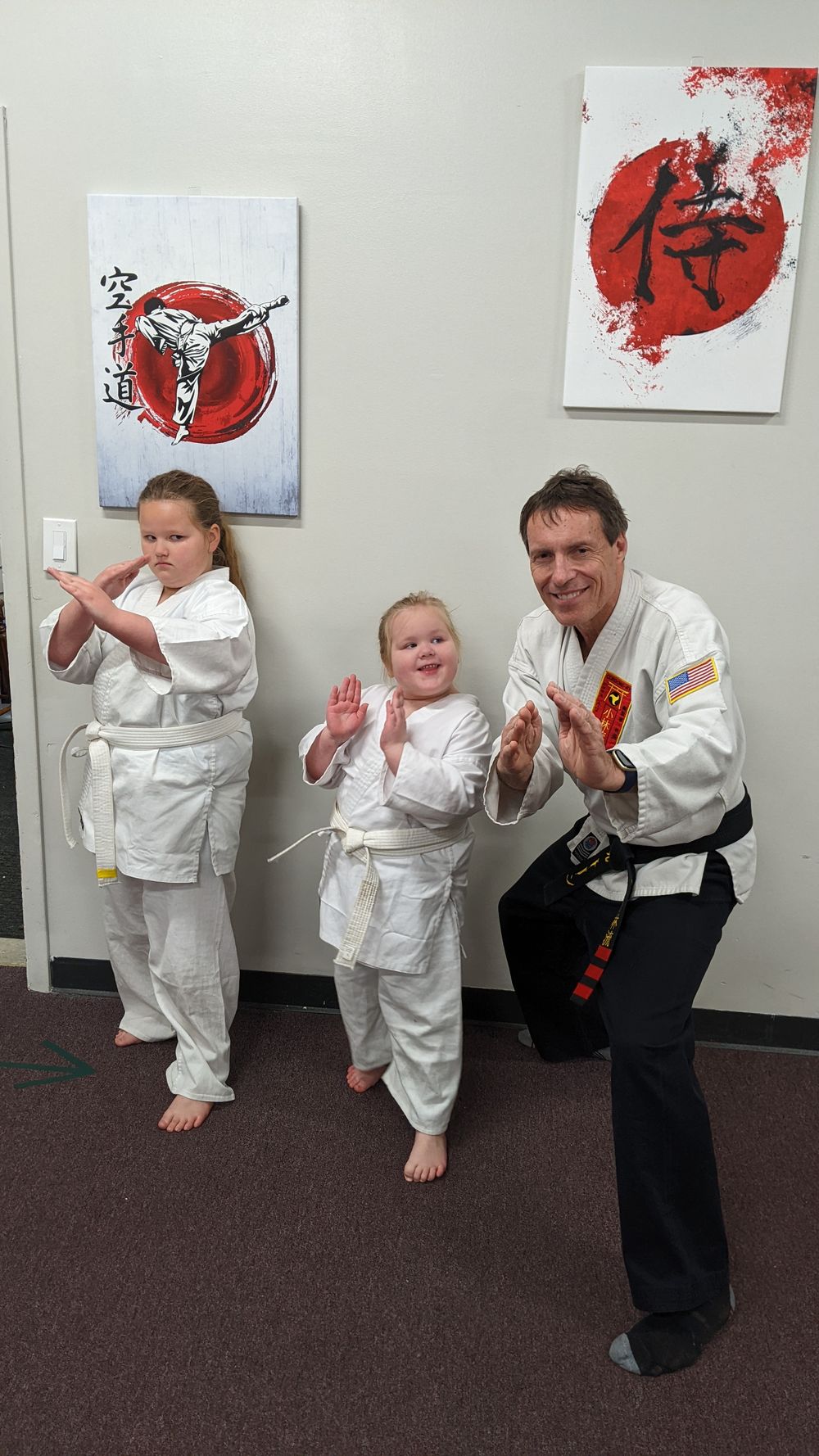 An instructor and two young students in the dojo