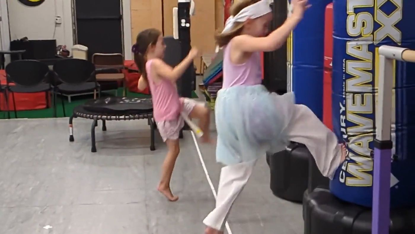 Young students practice kicks on a padded target