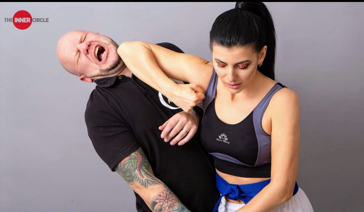 A woman practices a self-defense technique on an instructor